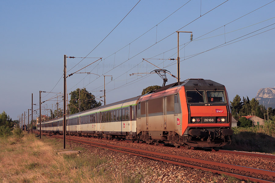 Traversée de la gare de Cuers du Corail Lunéa "Alsace-Riviera" 4297 Strasbourg - Nice-Ville, tracté par la BB 26168, éclairé par une lumière matinale.