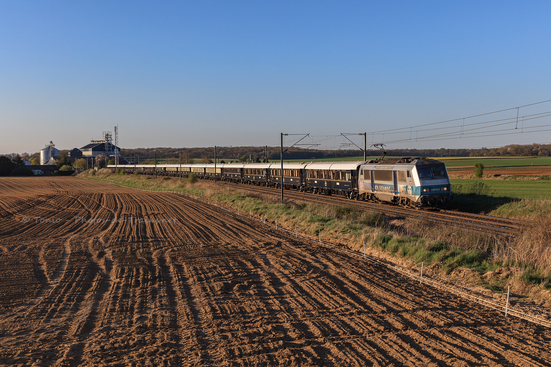 BB 26163 à la traction, le VSOE Calais - Bâle se présente dans la courbe de Gannes, dont il vient de traverser la gare.