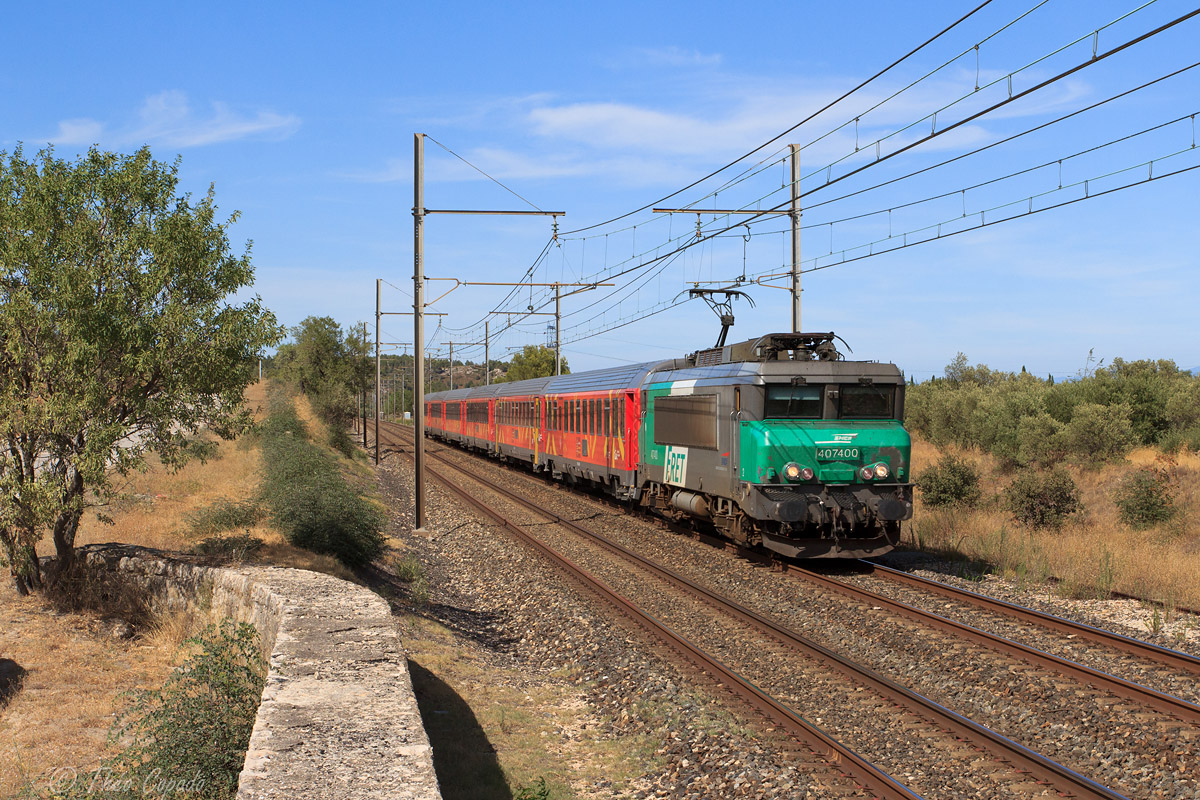 La BB 7400 en livrée FRET, désormais affectée à l'activité Voyageurs entre sud-est et sud-ouest, est vue sur ce TER Avignon - Cerbère, au crochet d'une rame Corail rouge aux couleurs de la région Languedoc-Roussillon.