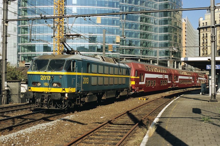 Tracté par le HLE 2013, le train d'heure de pointe 8602, composé de voitures du type M5, quitte Bruxelles-Schuman. Cette gare dessert le quartier des institutions européennes.