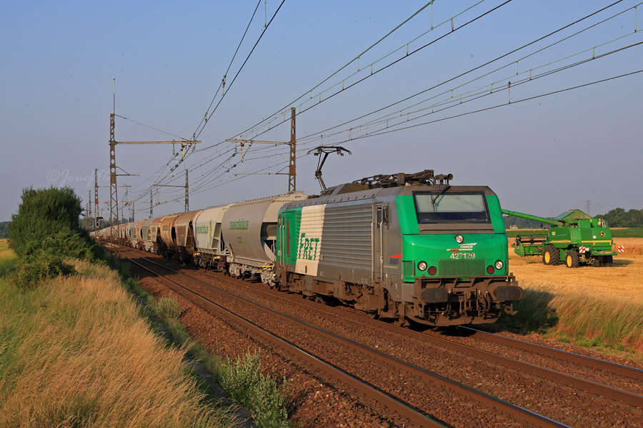 Une BB 27000 emm&egrave;ne une double rame de c&eacute;r&eacute;aliers &agrave; destination de Chartres. Celle-ci passe au c&ocirc;t&eacute; d'une moissoneuse-batteuse qui officiait dans le champs voisin peu de temps aupparavant.