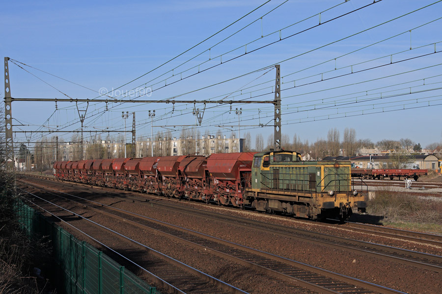 Un BB 63500 vert celtique tracte ce train de ballasti&egrave;res &agrave; essieux, vu juste apr&egrave;s son d&eacute;part de Trappes.