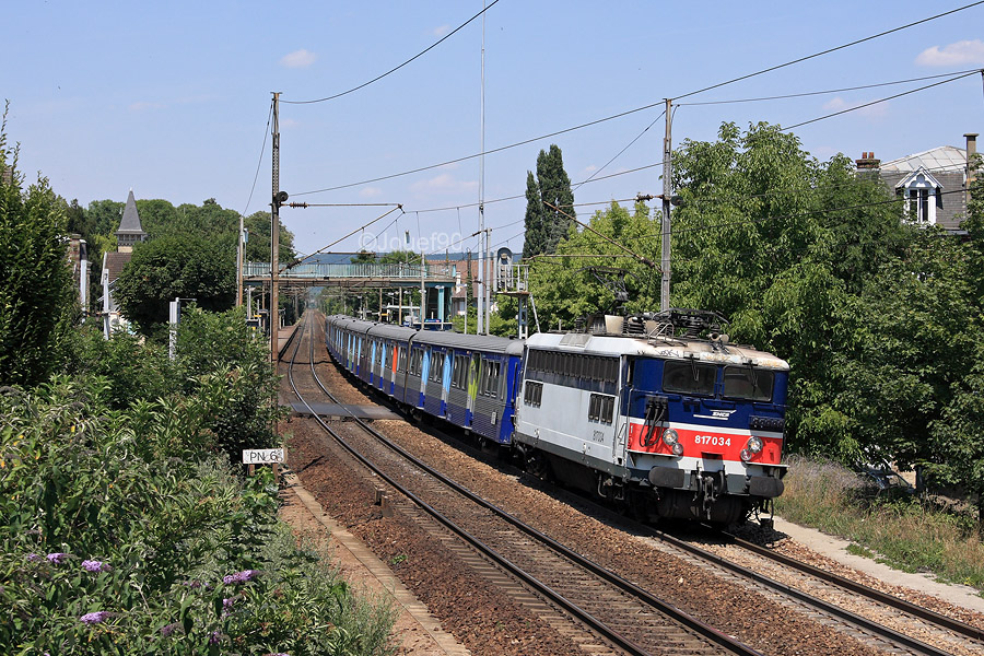 La BB 17034 emm&egrave;ne la RIB 65 sur une mission Mantes-la-Jolie - Paris-St-Lazare. Le train est vu quittant la gare de Villennes-sur-Seine.