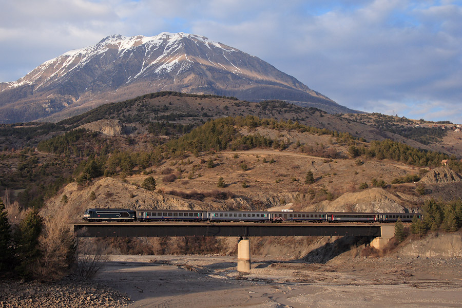 Le TER 17360 Brian&ccedil;on - Valence-Ville, assur&eacute; par le BB 67497 et une rame de voitures Corail, franchit le lac de Serre-Pon&ccedil;on temporairement ass&eacute;ch&eacute;, juste avant d'entrer en gare de Savines.