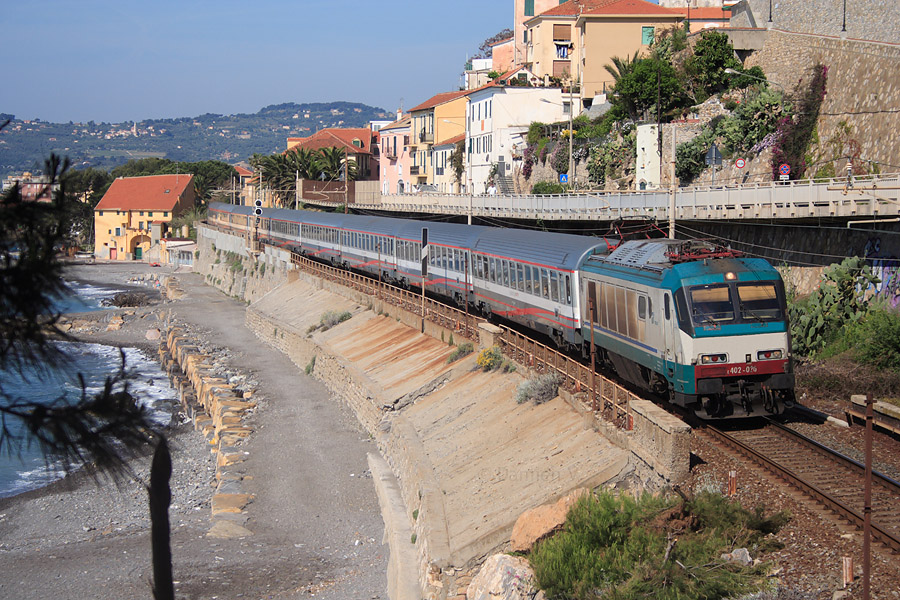 Compos&eacute; de la locomotive E402A 020 et de voitures fra&icirc;chement r&eacute;nov&eacute;es "Eurostar City", le train InterCity 657 reliant Ventimiglia &agrave; Milano Centrale se faufile entre le village de Cervo et la plage.