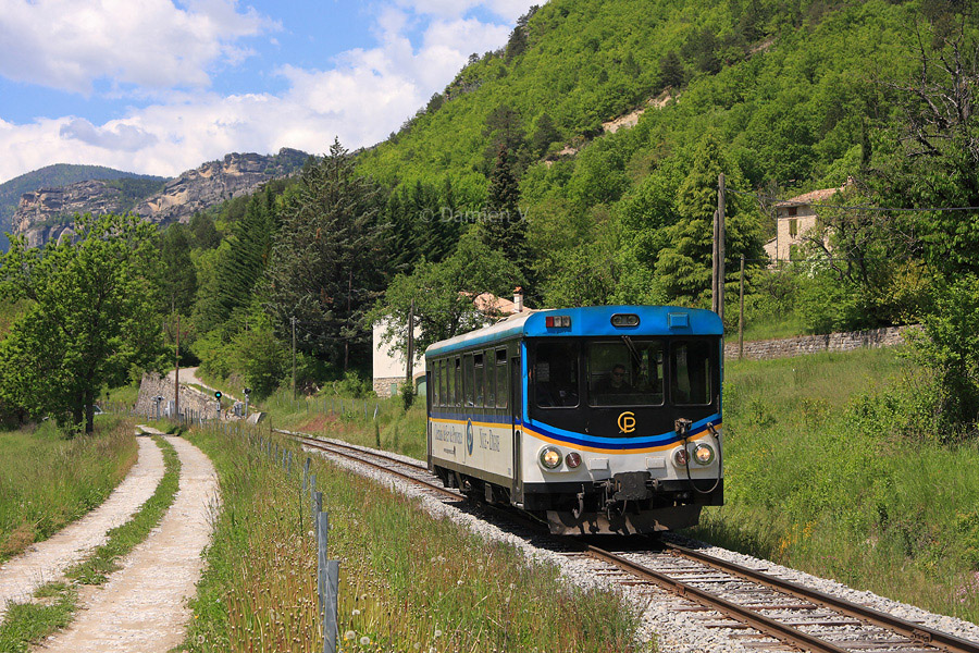 Assur&eacute; par l'X 303, le train N&deg;4 reliant Digne-les-Bains &agrave; Nice-CP est vu dans la verdure, peu avant la halte de Saint-Beno&icirc;t, arr&ecirc;t facultatif qu'il ne desservira pas cette fois-l&agrave;.