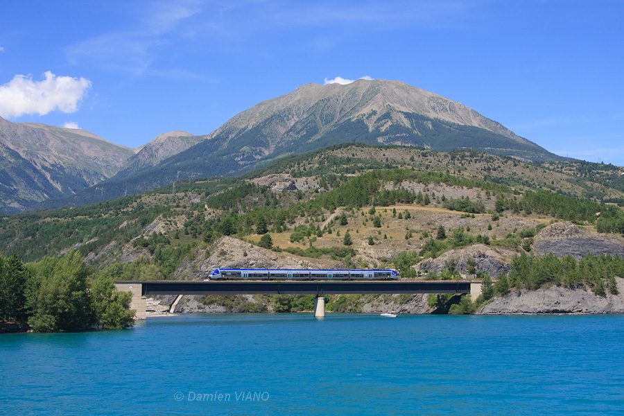 Le TER 17359 Romans-Bourg-de-Péage - Briançon est vu à Savines-le-Lac, franchissant le Lac de Serre-Ponçon.