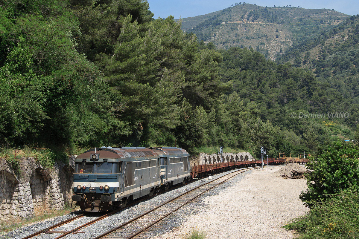 Les BB 67265 et 67226 quittent la gare de Drap-Cantaron, avec une rame de wagons plats destinés au transport de rails.