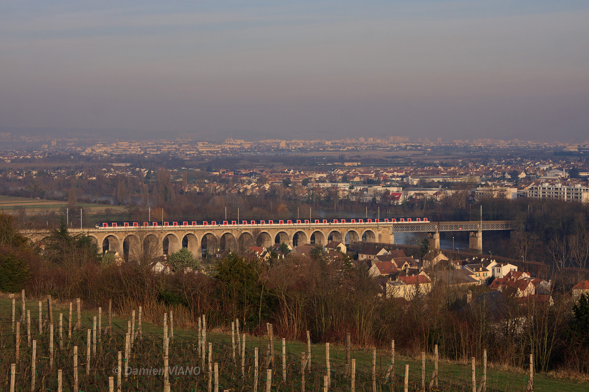 La mission ZEUS41 du RER A, composée de trois rames MS 61 en livrée d'origine, arrive à son terminus lorsqu'elle enjambe la Seine, sur la commune de St-Germain-en-Laye. Au premier plan, un vignoble tout jeune, planté en avril 2000 sous la grande Terrasse de St-Germain-en-Laye, qui renoue avec 1300 ans d'histoire viticole dans la région.