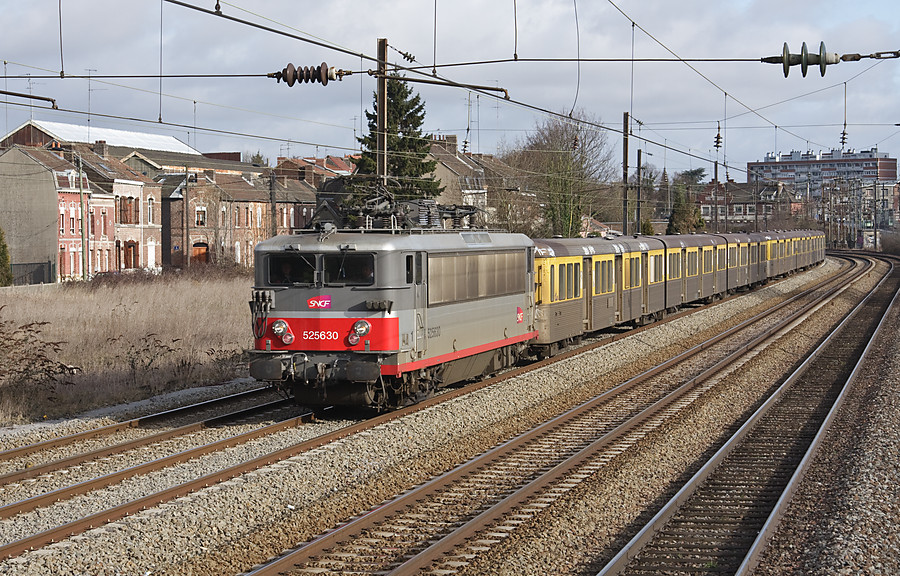 Venant de passer l'ancienne gare de Valenciennes-Faubourg-de-Paris (b&acirc;timent de brique visible au dessus de la queue du train), le TER pour Cambrai s'&eacute;lance sur le tronc commun &agrave; 4 voies en sortie de Valenciennes.