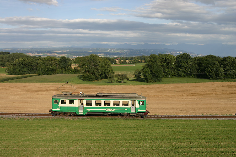 Petit train rural entre L&eacute;man et Jura, une automotrice BDe 4/4 du Bi&egrave;re-Apples-morges, datant de 1943, assure un train L'Isle-Mont-la-ville - Apples, sur fond de pr&eacute;-Alpes et de lac L&eacute;man, qu'on devine.