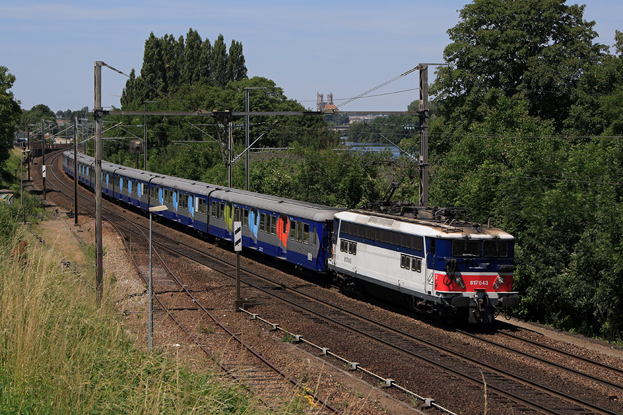La BB 17043 emmène une rame de RIB Transilien vers Paris-St-Lazare. Elle est vue longeant la Seine, du côté de Guerville.