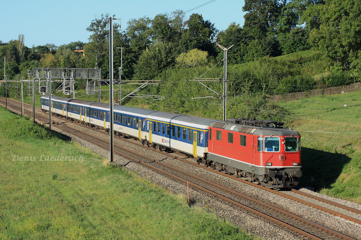 Une Re 4/4 II, avec des voitures unifiées type II, assure un train Regional-Express entre la cité de Calvin et la capitale Vaudoise. Cette composition est appelée à disparaitre sur cette relation, depuis l'arrivée des automotrices KISS RABe 511.