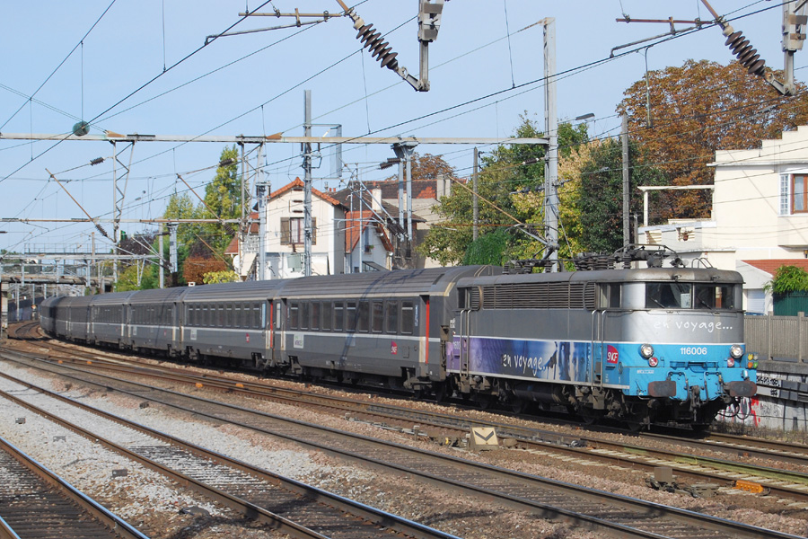La BB 16006 arborant la livr&eacute;e "En voyage" assure le Corail Intercit&eacute;s 3138 Le Havre - Paris Saint-Lazare. Le train s'appr&ecirc;te &agrave; passer &agrave; vive allure en gare de Houilles - Carri&egrave;res sur Seine.